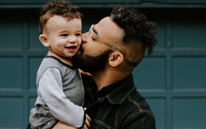 father holds and kisses his toddler son