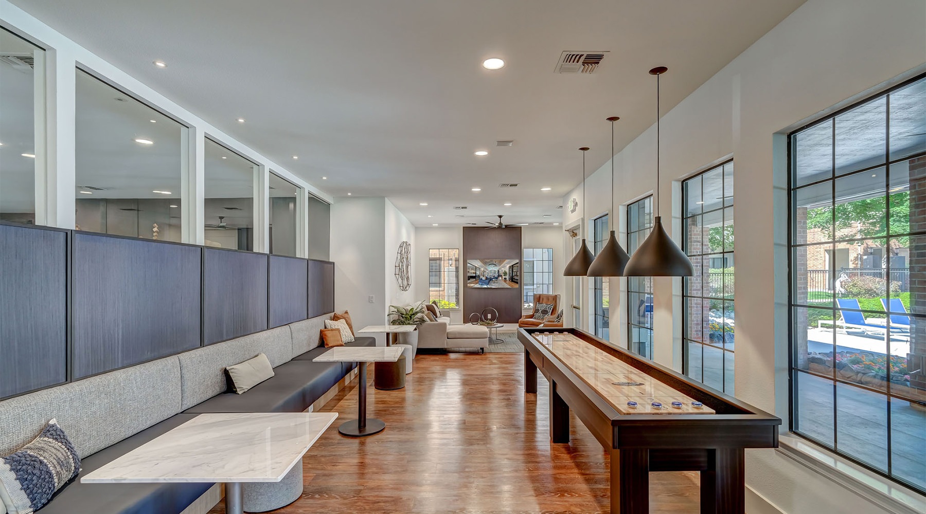 Game Room The game room at Cierra Crest Apartments includes a shuffleboard table, built-in booth seating, pendant lighting, and large windows.